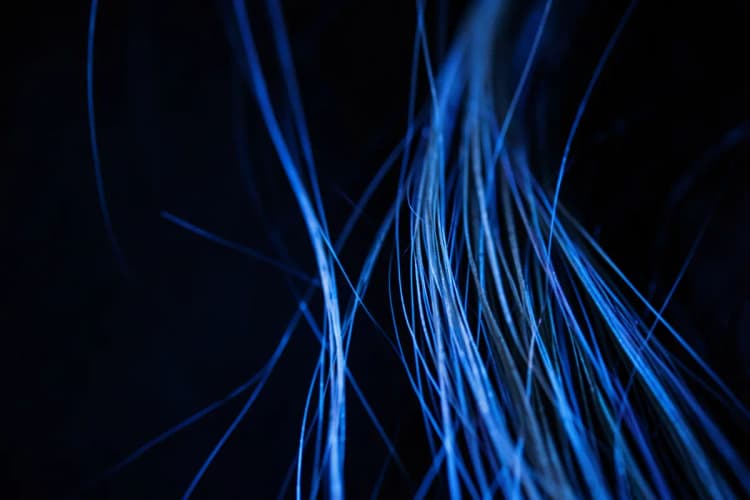 Fio de cabelo fino e grosso lado a lado, com um laser azul incidindo sobre o fio fino.