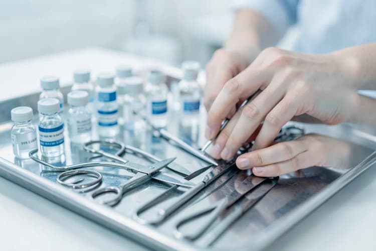 Profissional de saúde preparando equipamento médico em uma bandeja.